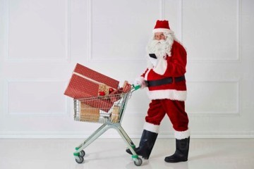 santa-claus-carrying-christmas-presents-in-a-shopping-cart-while-looking-at-cell-phone-abif00108.jpeg