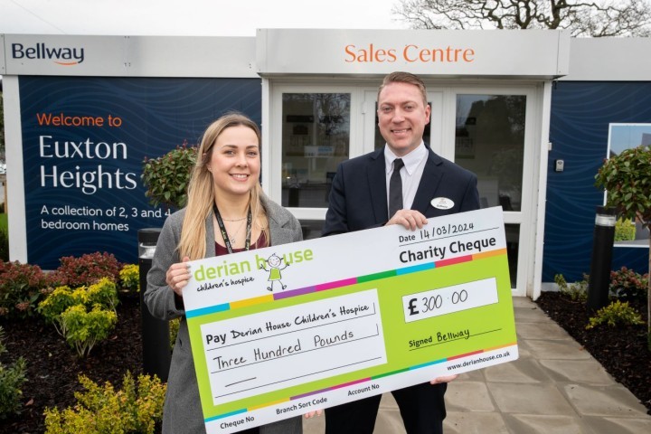 Derian House fundraiser Ellie receives the donation from Bellway sales advisor Josh SMALLER.jpg.jpg