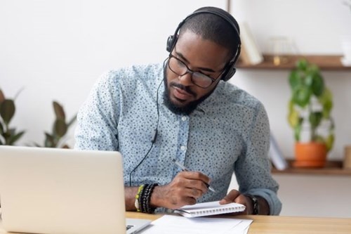 _a-man-taking-notes-while-looking-at-a-computer.jpg